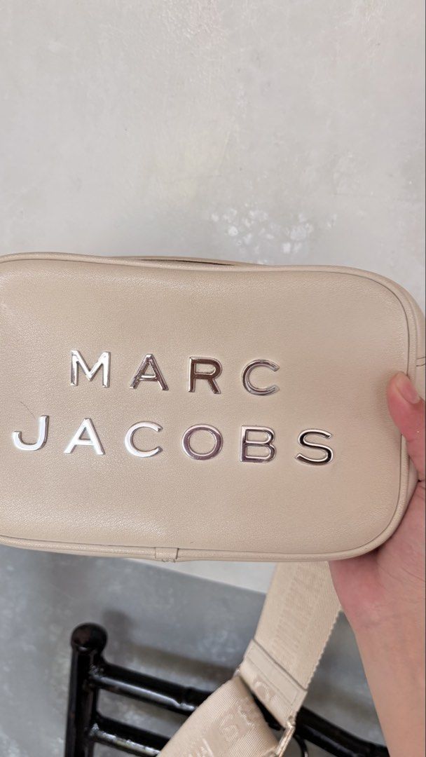 Marc Jacobs Cream Leather Camera Bag (Category: Luxury Bags & Wallets) located in Iba. Submitted by fruitypebblezz (Listing ID 1442913667, Image 2). Description: - Authentic Marc Jacobs cream leather camera bag - Features signature embossed logo on the front - Adjustable strap with repeating Marc Jacobs branding - Secure zipper closure - Clean and well-maintained interior -Has hardware discoloration - Ideal for everyday use and carrying essential