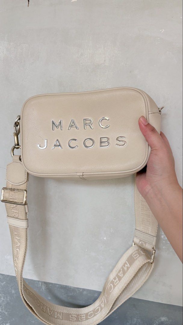 Marc Jacobs Cream Leather Camera Bag (Category: Luxury Bags & Wallets) located in Iba. Submitted by fruitypebblezz (Listing ID 1442913667, Image 1). Description: - Authentic Marc Jacobs cream leather camera bag - Features signature embossed logo on the front - Adjustable strap with repeating Marc Jacobs branding - Secure zipper closure - Clean and well-maintained interior -Has hardware discoloration - Ideal for everyday use and carrying essential