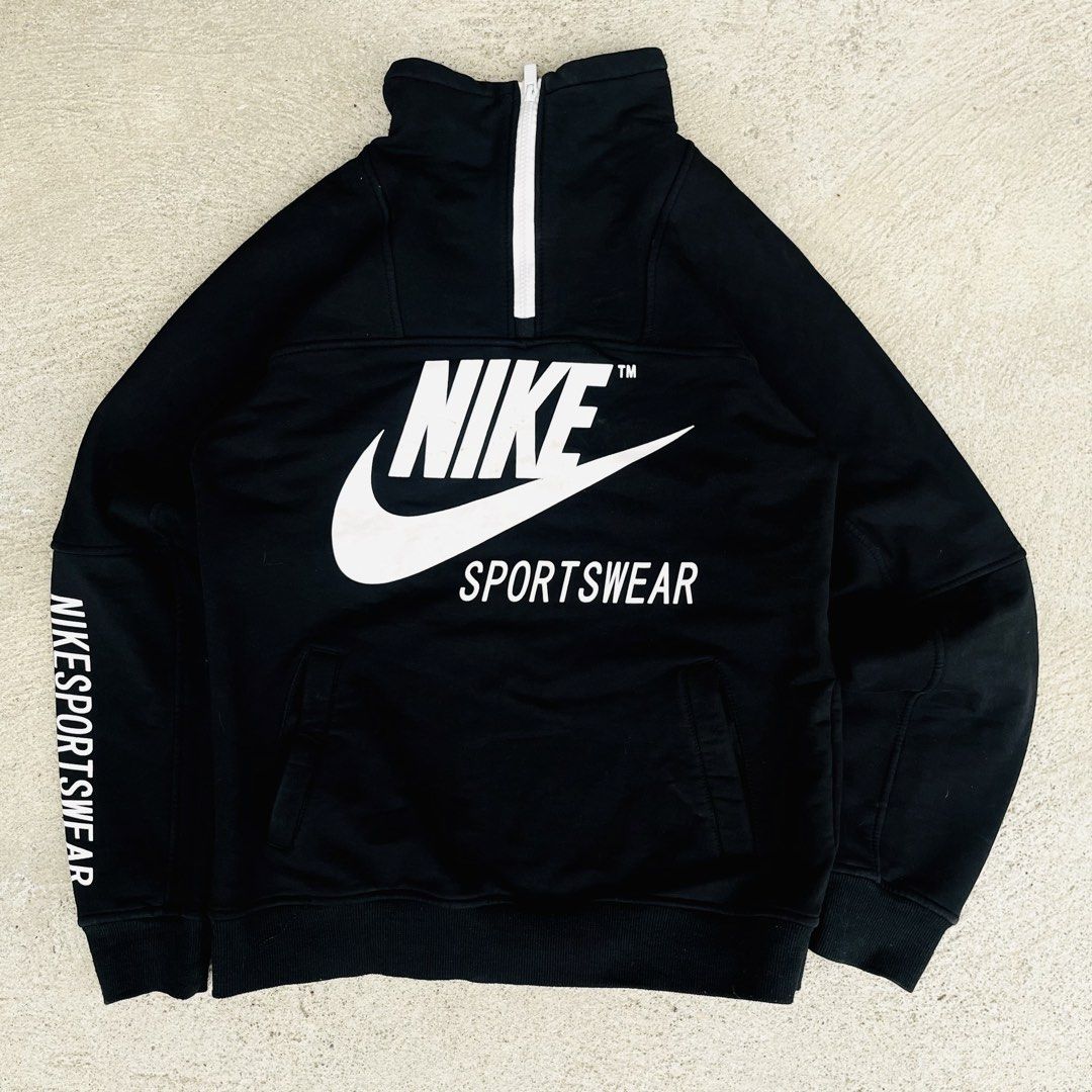 Nike Sportswear Half Zip Black Sweatshirt (Category: Coats, Jackets and Outerwear) located in Calamba. Submitted by aivhan.thrift (Listing ID 1442864530, Image 1). Description: - Black Nike Sportswear sweatshirt - Large white Nike logo and swoosh on front - 'NIKE SPORTSWEAR' text on sleeves - Front pocket - Half-zip closure at the neck - Ideal for casual wear.