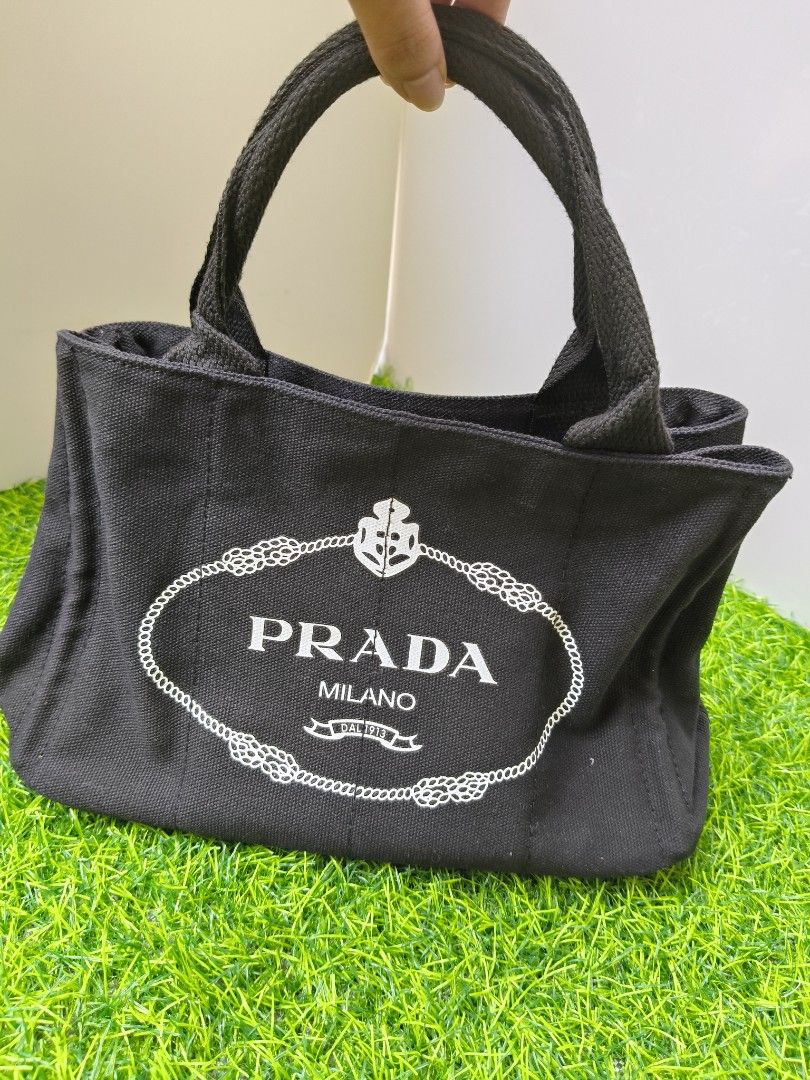 Prada Milano Black Canvas Tote Bag (Category: Luxury Bags & Wallets) located in Manila. Submitted by babylyn85 (Listing ID 1442732328, Image 1). Description: - Classic black Prada tote bag - Durable canvas material - Iconic Prada Milano logo on the front - Interior zipped pocket - Two side pockets - Sturdy and comfortable handles - Ideal for everyday use or travel.