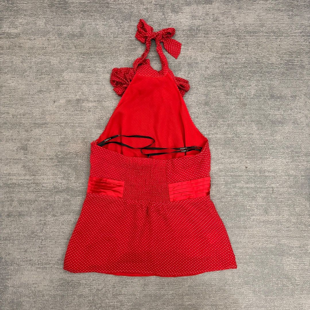 Y2K Bebe Res Silk Polka Dot Halter Tops (Category: Others Tops) located in Calamba. Submitted by bermuda.ph (Listing ID 1442796162, Image 2). Description: The selected garment is a vintage Y2K Bebe red silk polka dot halter top. It features an oversized decorative front bow at the neckline, a ruched/pleated satin waistband accent, a tie-back halter neck, and a slightly flared peplum hem. .