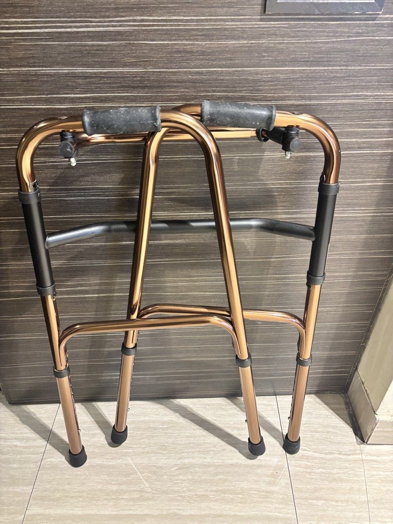 Adjustable Folding Walker (Category: Rehabilitative Devices) located in Singapore. Submitted by zblstore (Listing ID 1446965310, Image 2). Description: - Adjustable height folding walker - Bronze frame - Black handles - Folds for easy storage and transport - Ideal for mobility assistance.