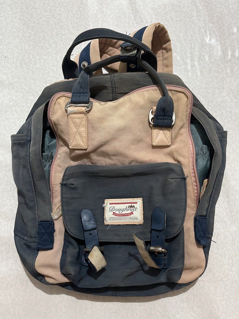 Doughnut Backpack (Category: Backpacks) located in Caloocan City. Submitted by ryspace (Listing ID 1447078659, Image 1). Description: - Brand: Doughnut - Colorway: Navy blue and pink - Features: Multiple pockets, buckle closures on front, adjustable straps - Condition: Some signs of wear, but still functional - Ideal for: Everyday use or travel - Capacity: 18L.