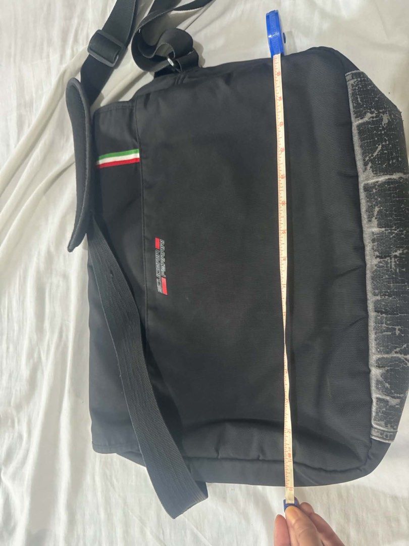 Ferrari Messenger Bag (Category: Luxury Bags & Wallets) located in Mandaluyong City. Submitted by gabbie_0708 (Listing ID 1447011528, Image 2). Description: - Iconic Ferrari shield logo, authentic - Black messenger bag with red accents - Italian flag colors on the front flap - Adjustable strap for comfortable wear - Ample interior space - Ideal for everyday use or travel Issue: faded buttom but you can replace it with leather.