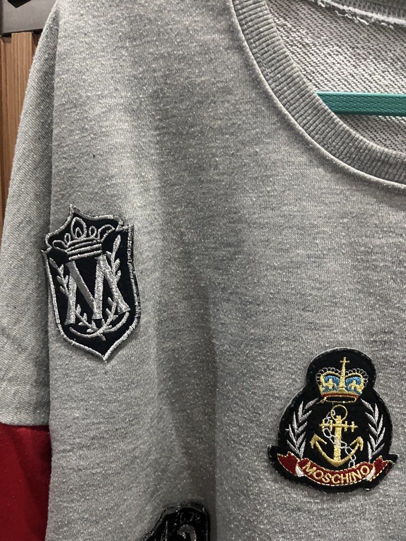 Grey Moschino Patch Sweatshirt with Red & Black Sleeves (Category: Longsleeves) located in Manila. Submitted by lucaaaa_ (Listing ID 1447035332, Image 2). Description: Cool grey sweatshirt with unique patches (Moschino, skull & crossbones, crests). Red/black sleeves. Crew neck. medium to large frame .