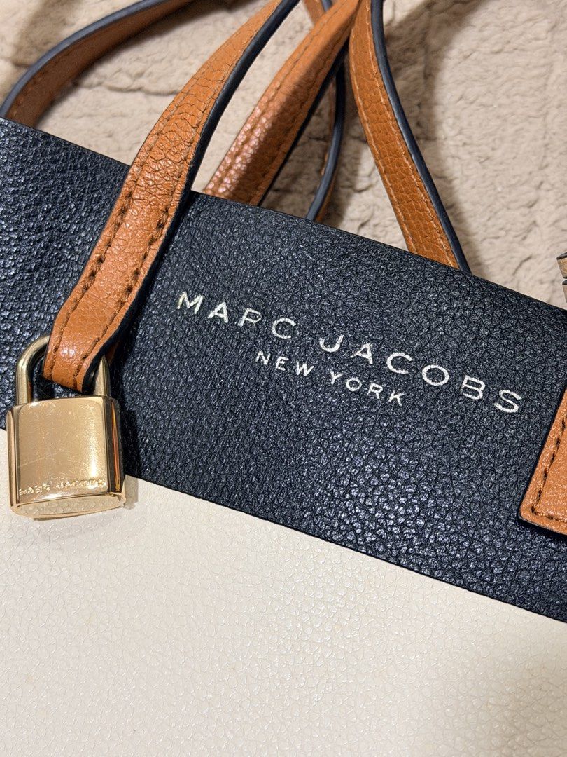 Marc Jacobs Mini Grind Tote Bag (Category: Luxury Bags & Wallets) located in Angeles City. Submitted by simplycatchy (Listing ID 1446949247, Image 3). Description: - Authentic Marc Jacobs tote bag - Chic black and cream leather with tan accents - Includes decorative padlock and key - Ample interior space for essentials - Ideal for everyday style and practicality.