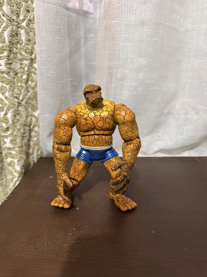 Marvel Fantastic Four The Thing Action Figure (Category: Figurines & Statues) located in Quezon City. Submitted by elektra0111 (Listing ID 1447100839, Image 1). Description: - Iconic Thing action figure from Marvel's Fantastic Four. - Features a textured, rocky orange body. - Comes with classic blue shorts. - Fully articulated joints for dynamic posing. - A must-have for any Marvel fan's collection. - Stands independently for easy display. - Read