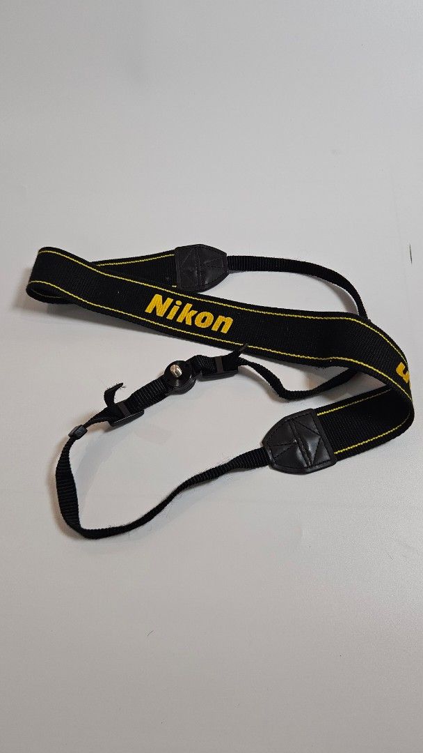 Nikon Camera Strap Black Yellow Adjustable Neck Shoulder Strap (Category: Camera Bags & Carriers) located in Alfonso. Submitted by jbcamet (Listing ID 1447029412, Image 1). Description: - Genuine Nikon camera strap - Color: Black with yellow Nikon lettering - Adjustable length for neck or shoulder wear - Features quick-release clips for easy attachment/detachment - Secure screw mount attachment - Ensures safe and comfortable carrying of your Niko