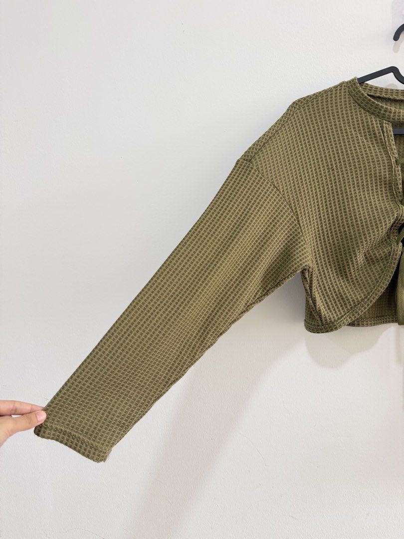 Olive Green Waffle Knit Lace-Up Outerwear (Category: Longsleeves) located in Petaling Jaya. Submitted by beautinaaa (Listing ID 1447096347, Image 2). Description: - Olive green outerwear - Waffle knit texture - Lace-up detail at front neckline - Long sleeves - Versatile for pairing with skirts or high-waisted pants - Ideal for casual outings.