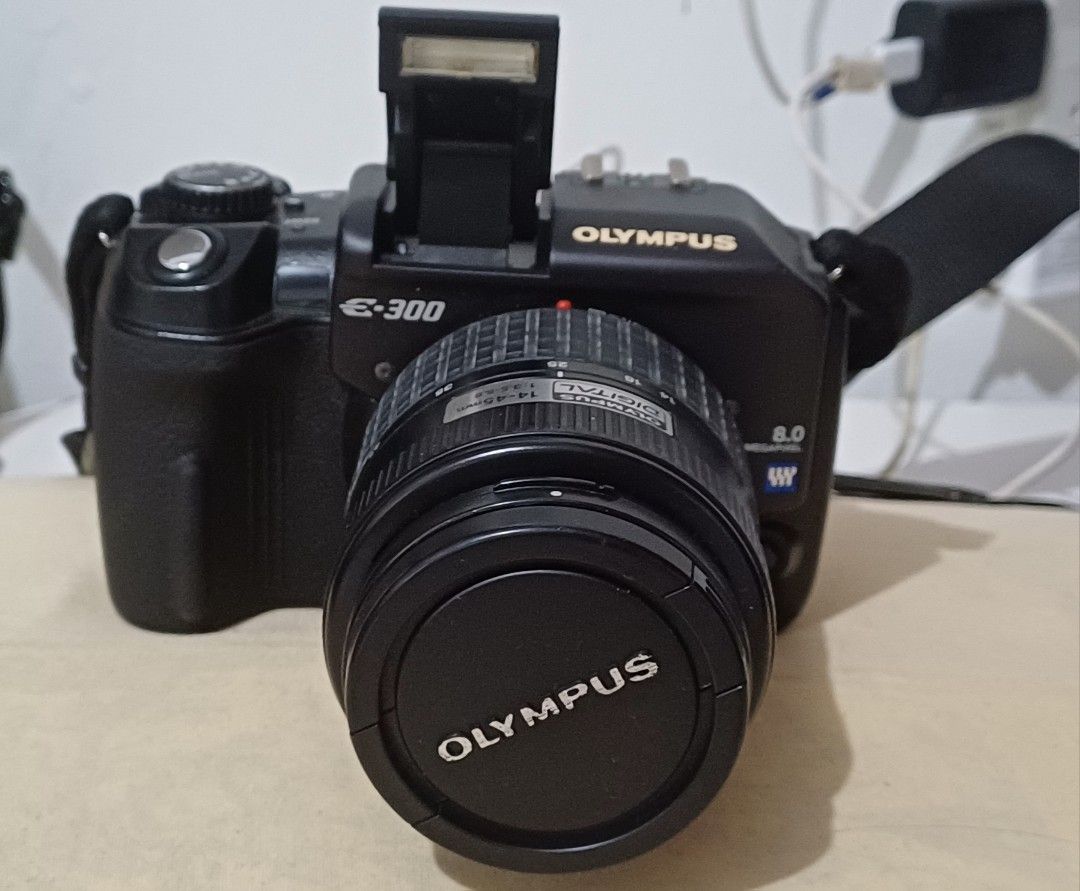 Olympus E-300 Digital SLR Camera with 14-45mm Lens (Category: Cameras) located in Quezon City. Submitted by mset.05011984 (Listing ID 1446964212, Image 1). Description: - Olympus E-300 DSLR camera - Zuiko Digital 14-45mm 1:3.5-5.6 lens included - 2GB CompactFlash card - Built-in pop-up flash - HyperCrystal LCD screen - Includes strap and lens cap - Perfect for your photography needs.