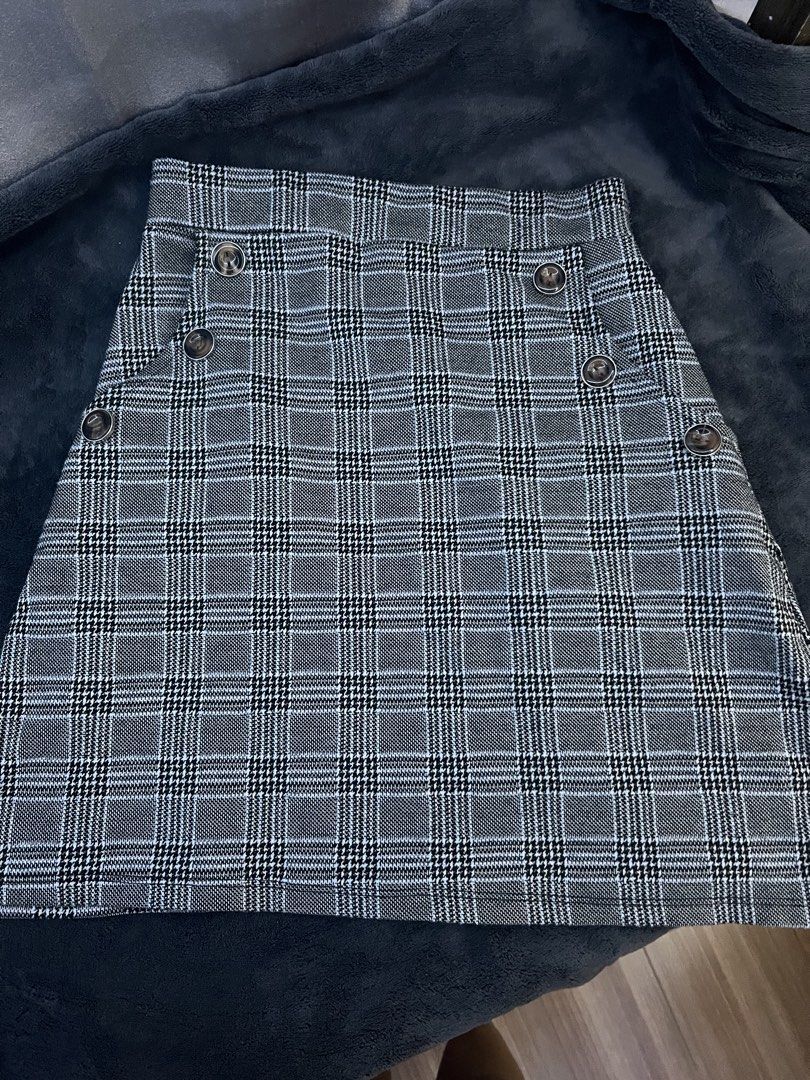 Plaid Button Detail A-Line Skirt (Category: Skirts) located in Pasig City. Submitted by nianaaa_ (Listing ID 1447087504, Image 2). Description: - Small can fit up to Medium - Stretchable - Grey and black plaid pattern - Features button details on the front - Flattering A-line cut - Estimated size: Small to Medium - Versatile for casual or dressed-up looks.