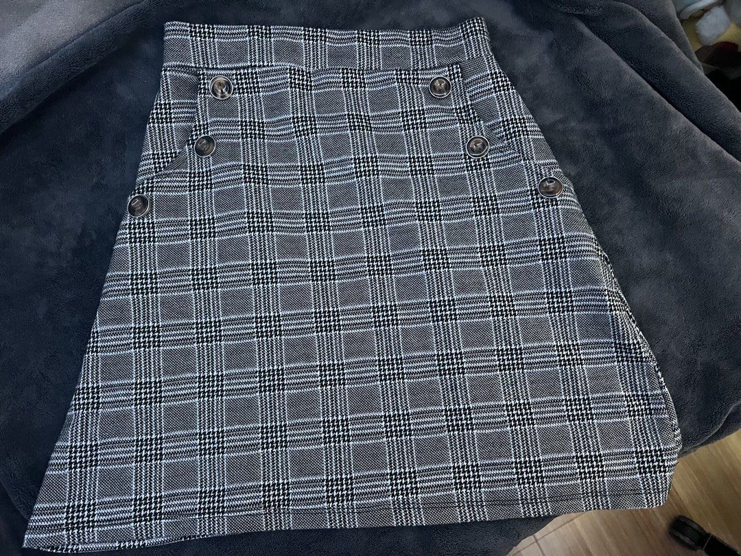 Plaid Button Detail A-Line Skirt (Category: Skirts) located in Pasig City. Submitted by nianaaa_ (Listing ID 1447087504, Image 1). Description: - Small can fit up to Medium - Stretchable - Grey and black plaid pattern - Features button details on the front - Flattering A-line cut - Estimated size: Small to Medium - Versatile for casual or dressed-up looks.