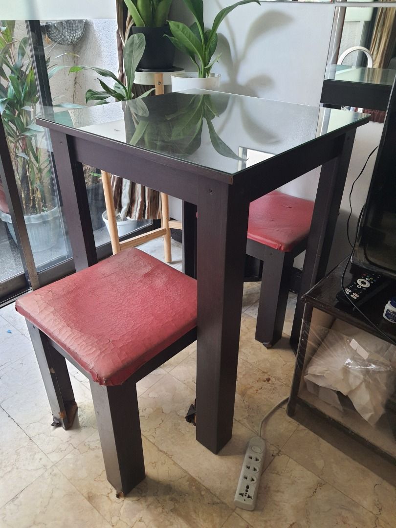 Table with glass top with 2 Red Stool Chairs (Category: Tables & Sets) located in Caloocan City. Submitted by bravemountain_ddc4bf (Listing ID 1447038877, Image 1). Description: - Clear glass tabletop - Includes 2 stool chairs - Ideal for small spaces - Note: Some wear on chair upholstery.