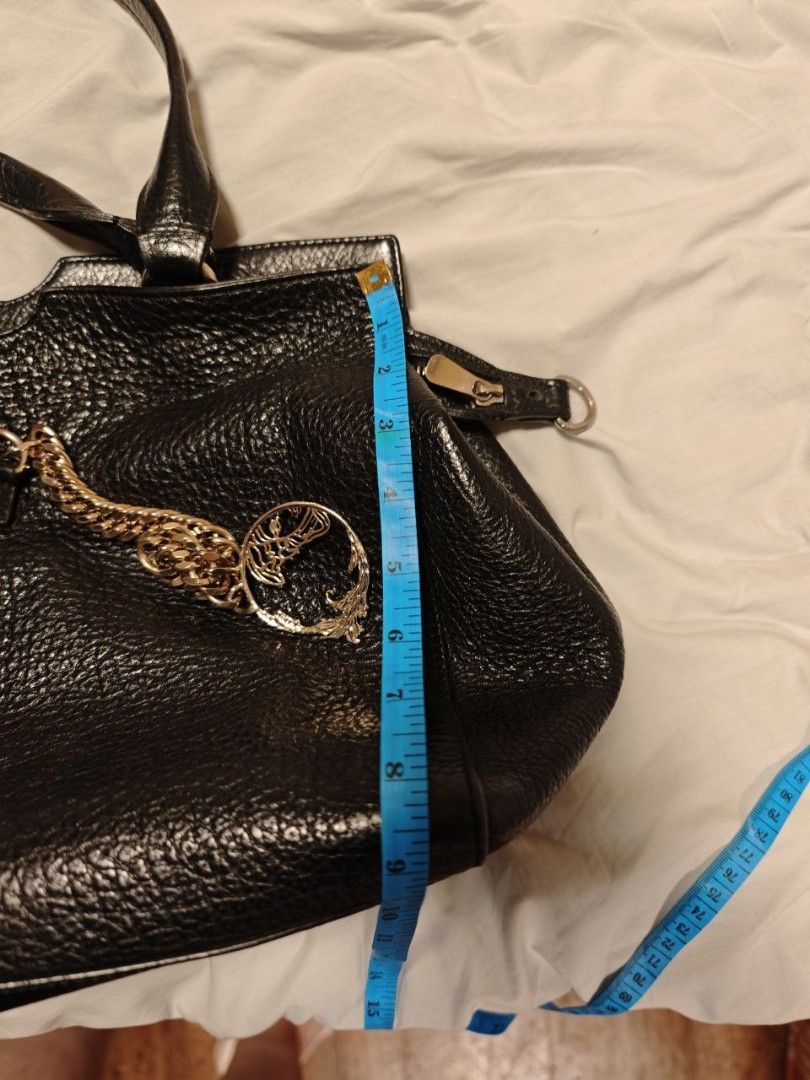 Versace Black Bag (Category: Luxury Bags & Wallets) located in Quezon City. Submitted by liz11888 (Listing ID 1447068252, Image 3). Description: This is a Versace Collection black leather tote bag. Key Features Material: Textured black leather Hardware: Silver-toned metal accents Design: Dual top handles, detachable shoulder strap, and a prominent Medusa pendant hanging from a thick chain link RFS: Saving for a new bag Perfect for an everyday off