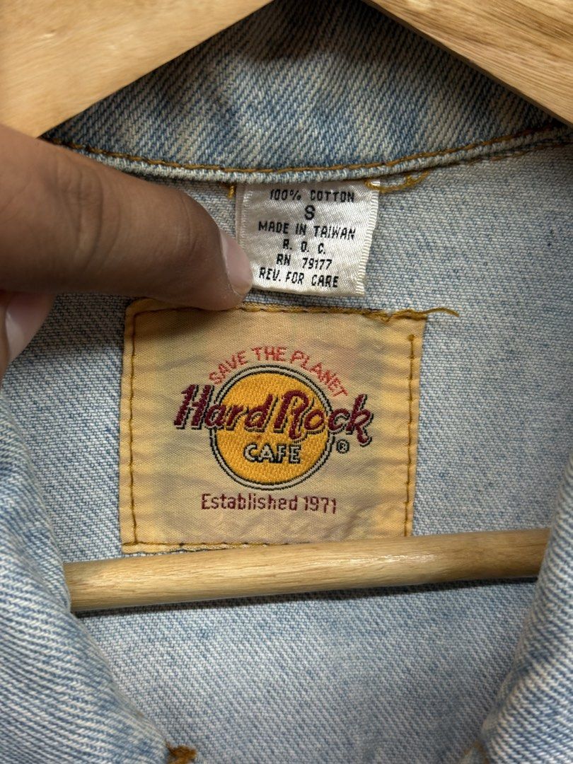Vintage Hard Rock Cafe Denim Jacket (Category: Coats, Jackets and Outerwear) located in Legazpi City. Submitted by deadthrift (Listing ID 1447007874, Image 3). Description: - Classic light wash denim jacket - Dimensions: 22.5 | 25 - Features iconic Hard Rock Cafe logo patch - Made of 100% cotton - Button closure and chest pockets - Established 1971 - Dry clean only - A great staple piece for any wardrobe.