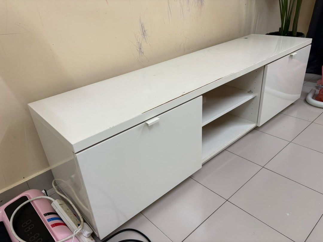 White TV Console with Storage (Category: TV Consoles) located in Ampang. Submitted by nanadaryan21 (Listing ID 1447033285, Image 1). Description: - Ikea Modern white TV console - Features two cabinet doors for concealed storage - Open shelving for media devices and accessories - Spacious top surface for TV placement - Plenty of storage space overall - Simple and modern design - Minor scuffs present on the top surface and the wall behind.