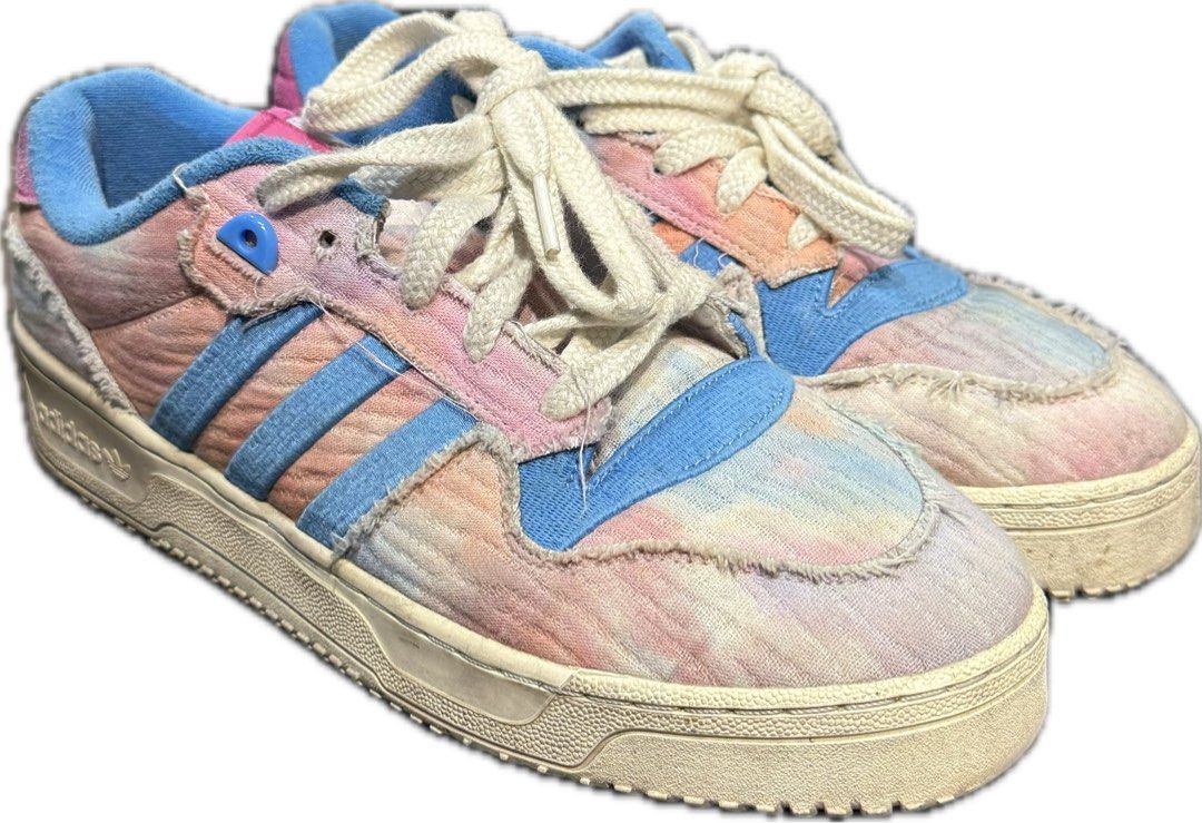 Adidas Rivalry Low Tie-Dye Sneakers (Category: Sneakers) located in Pasig City. Submitted by thisisfnjoy (Listing ID 1448890252, Image 1). Description: - Adidas Rivalry Low sneakers -Size 11 -8/10 only needs cleaning -Soles still good and thick - Unique tie-dye pattern - Blue Adidas stripes - Pink/purple heel accents - Distinctive frayed fabric edges - White laces - Ideal for casual wear.