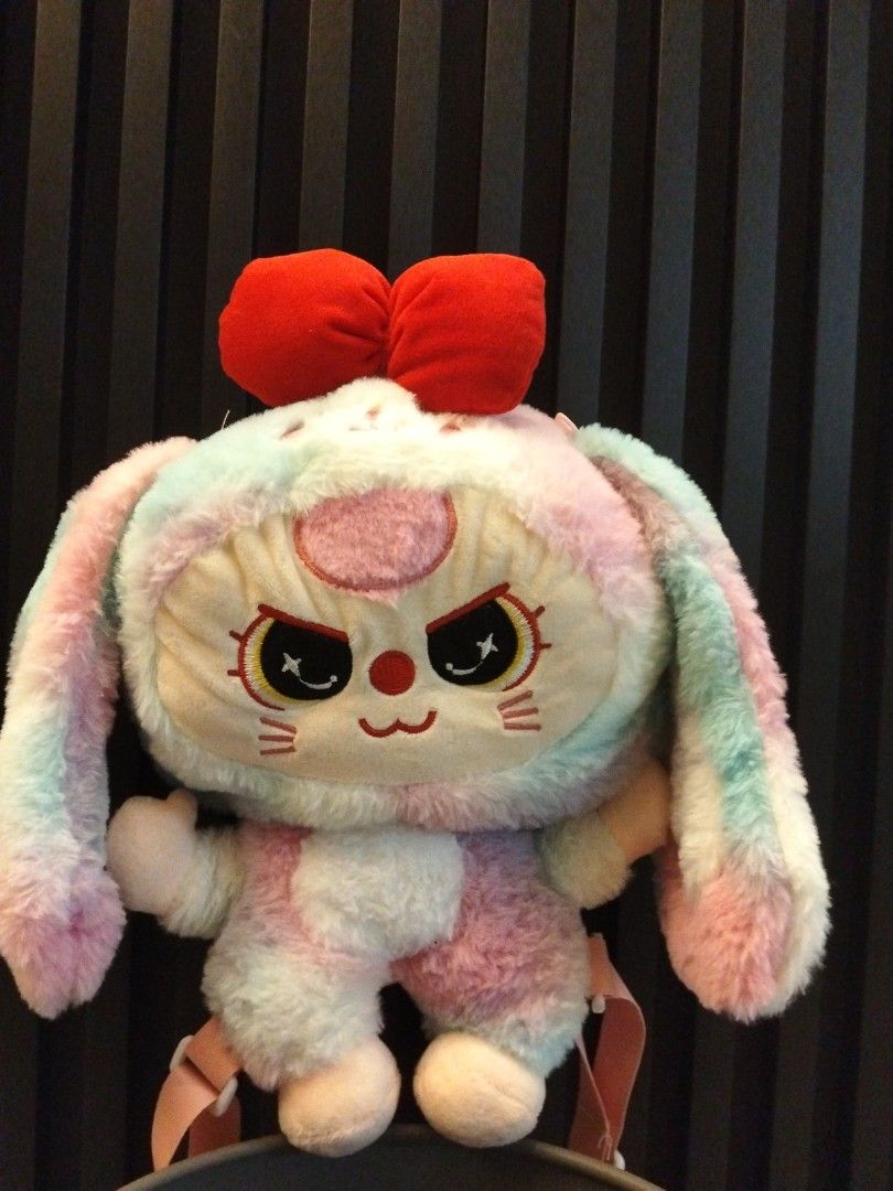 Cute Rainbow Bunny Plush Backpack with Red Bow (Category: Backpacks) located in Kuantan. Submitted by fahana02 (Listing ID 1448841023, Image 1). Description: - Adorable rainbow bunny plush backpack - Unique grumpy face with star eyes - Decorated with big red bows - Eye-catching pastel rainbow colors - Comfortable pink straps - Ideal for carrying small essentials or as a cute accessory.