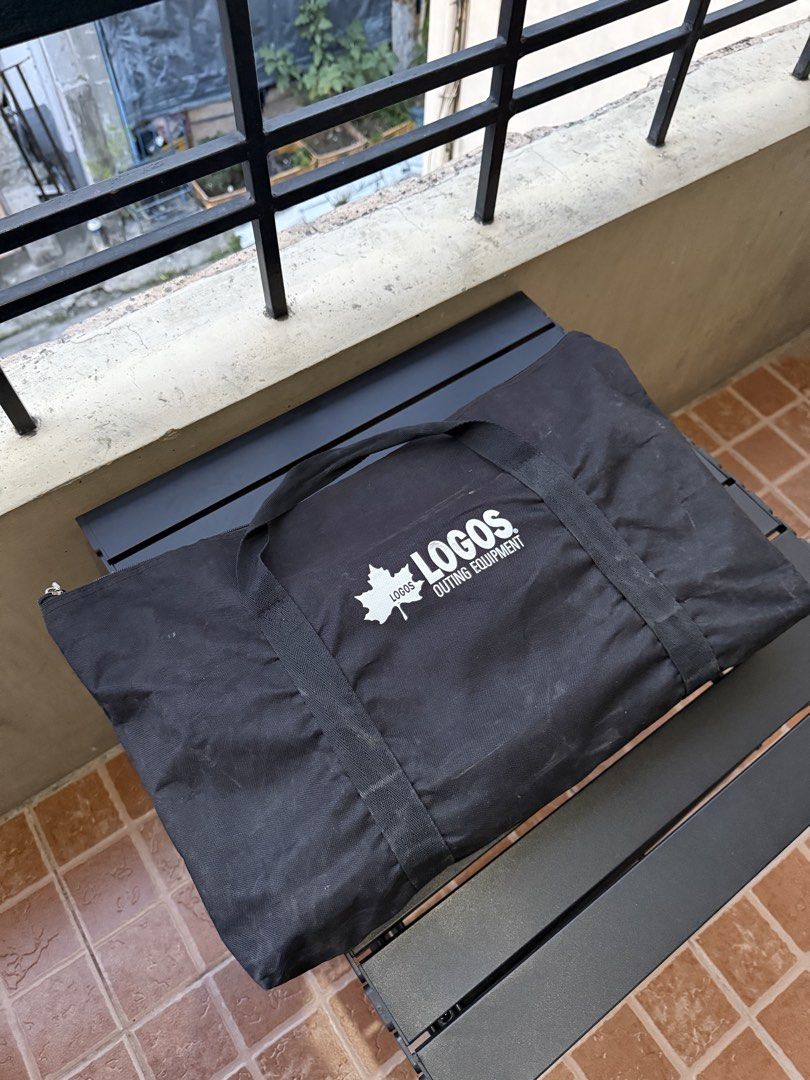 LOGOS Portable BBQ Grill with Carry Bag (Category: Hiking & Camping) located in Paranaque City. Submitted by lourdel018 (Listing ID 1448838561, Image 1). Description: - LOGOS portable BBQ grill - Includes black carry bag - Perfect for outdoor cooking and camping - Durable stainless steel construction - Comes with grill grate and charcoal tray - Folds compactly for easy transport - Shows minor signs of use on metal, fully functional.