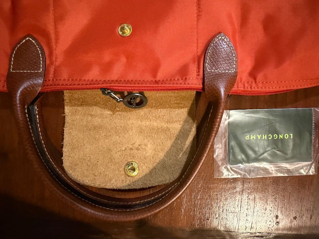 Longchamp Le Pliage Tote Bag Orange (Category: Luxury Bags & Wallets) located in Cavite. Submitted by carizhai (Listing ID 1448800940, Image 3). Description: - Authentic Orange Longchamp tote bag - Genuine leather handles and trim - Interior pockets for organization - Secure snap button closure - Folds flat for easy storage - Ideal for travel and everyday use - Rustan’s ATC bought (before it became Rockwell) 😉 - RFS: Downsizing to two colors onl