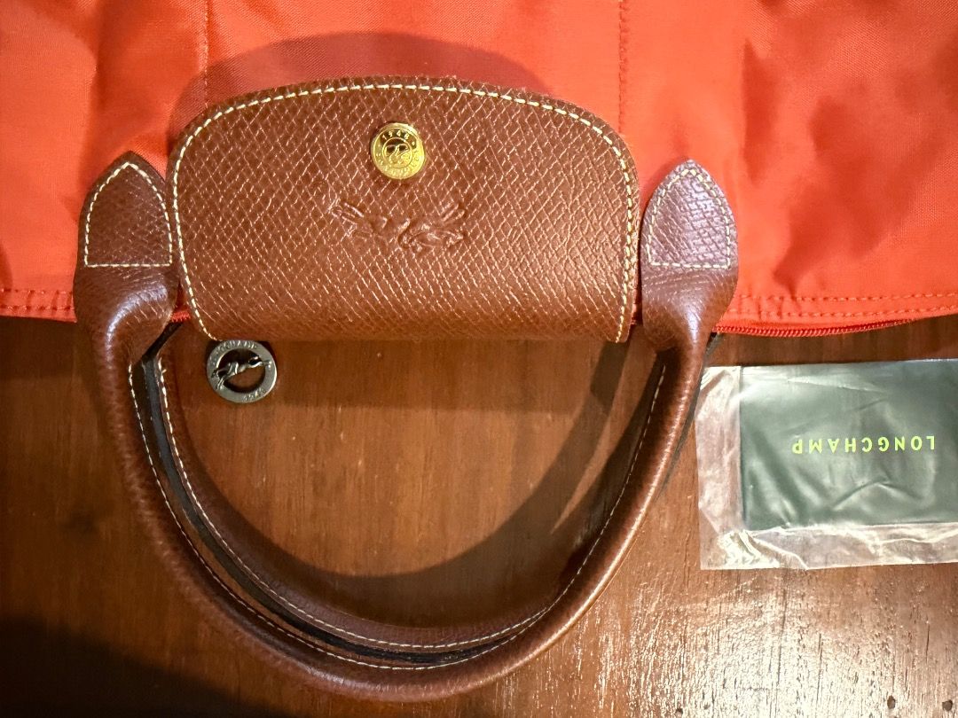 Longchamp Le Pliage Tote Bag Orange (Category: Luxury Bags & Wallets) located in Cavite. Submitted by carizhai (Listing ID 1448800940, Image 2). Description: - Authentic Orange Longchamp tote bag - Genuine leather handles and trim - Interior pockets for organization - Secure snap button closure - Folds flat for easy storage - Ideal for travel and everyday use - Rustan’s ATC bought (before it became Rockwell) 😉 - RFS: Downsizing to two colors onl