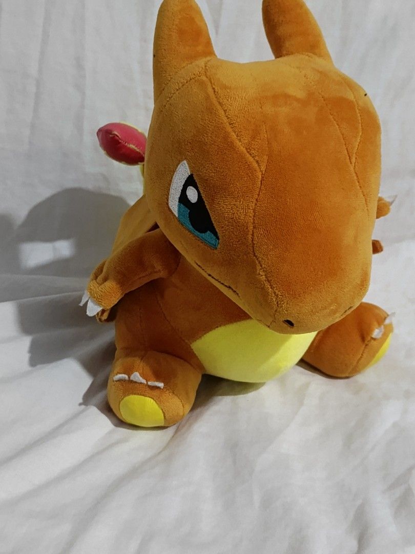 Pokemon Charizard Plush Toy (Category: Plushies & Soft Toys) located in Caloocan City. Submitted by just_thrift_thing (Listing ID 1448878436, Image 2). Description: - Orange Charizard plush toy - Big blue eyes and yellow belly - Wings on the back - Flame detail on the tail - Soft and cuddly material - Ideal for Pokemon fans - Suitable for display or play.
