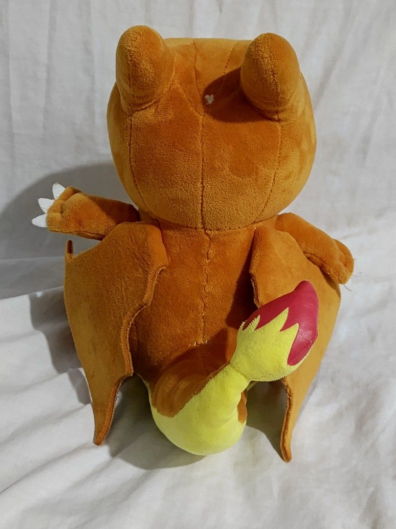 Pokemon Charizard Plush Toy (Category: Plushies & Soft Toys) located in Caloocan City. Submitted by just_thrift_thing (Listing ID 1448878436, Image 3). Description: - Orange Charizard plush toy - Big blue eyes and yellow belly - Wings on the back - Flame detail on the tail - Soft and cuddly material - Ideal for Pokemon fans - Suitable for display or play.