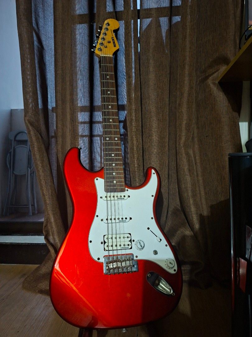 Red Busker's Electric Guitar (Category: Musical Instruments) located in Paranaque City. Submitted by ghanreagan15.1 (Listing ID 1448806273, Image 3). Description: - Red electric guitar - Stratocaster style body - White pickguard - Silver hardware note: slightly rust hardware wilkinson humbucker pickups comes with padded gig bag worth 1.5k guitar stand guitar strap tremolo - 'Busker's' brand on headstock - Ready for a new owner.