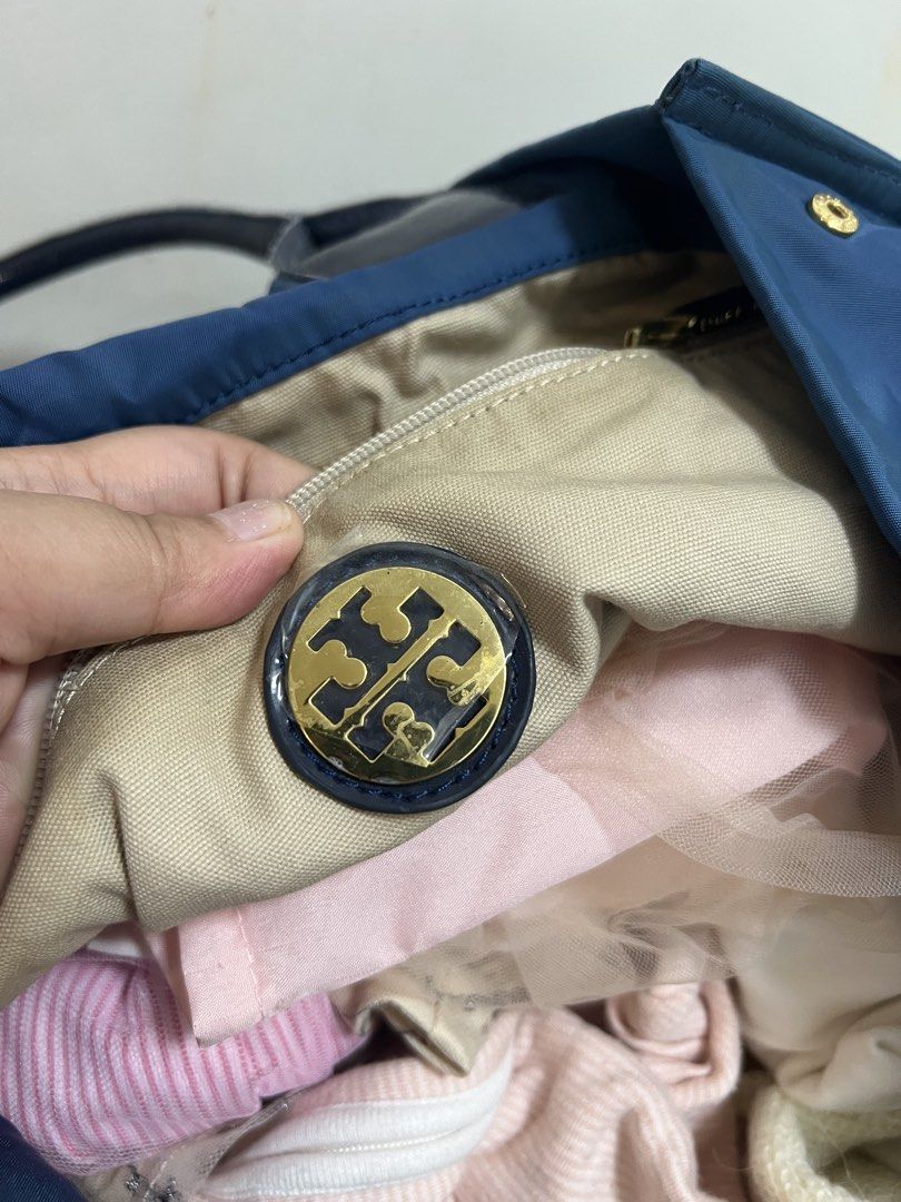 Tory Burch Nylon Tote Bag Navy Blue (Category: Luxury Bags & Wallets) located in Manila. Submitted by gailmg (Listing ID 1448785465, Image 2). Description: - Authentic Tory Burch - Navy blue Tory Burch tote bag - Durable nylon material with patent leather trim - Prominent Tory Burch logo on the front - Interior zip pocket for secure storage - Patent leather handles - Patent leather protection on bottom corners - Ideal for everyday use.