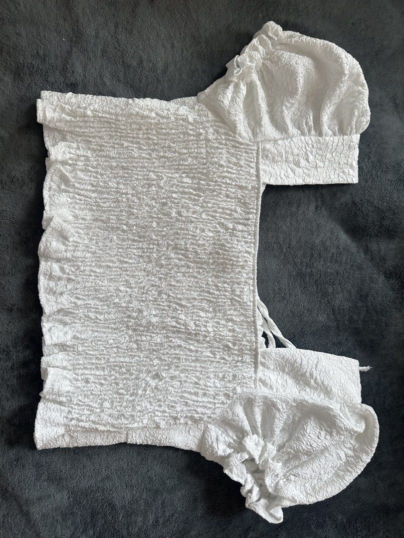 White Textured Puff Sleeve Crop Top with Tie Back (Category: Blouses) located in Taguig. Submitted by stigmapanda (Listing ID 1448824667, Image 2). Description: - Measurements are in cm - White textured crop top - Features puff sleeves - Stylish tie-back detail - Row of small buttons down the front - Crinkled fabric for a unique look - Approx. measurements: 43cm length, 44cm bust, 14cm sleeve length, 20cm hem.
