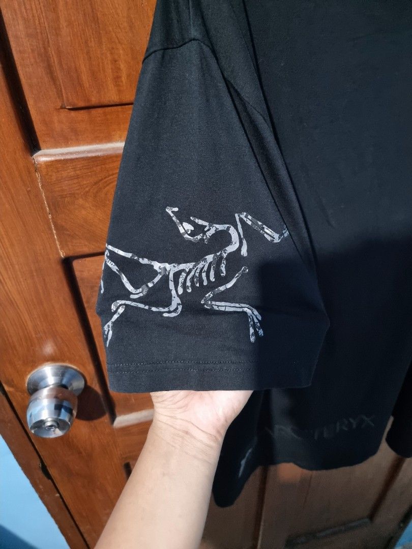 Arc'teryx Black Graphic T-Shirt (Category: Tshirts & Polo Shirts ) located in Villaverde. Submitted by ejaythrift (Listing ID 1448990393, Image 3). Description: - Brand: Arc'teryx - Color: Black - Style: Long-sleeve t-shirt - Features: Iconic Arc'teryx logo and skeleton graphic on sleeves - Origin: Made in China - Best for: Casual wear, outdoor activities.