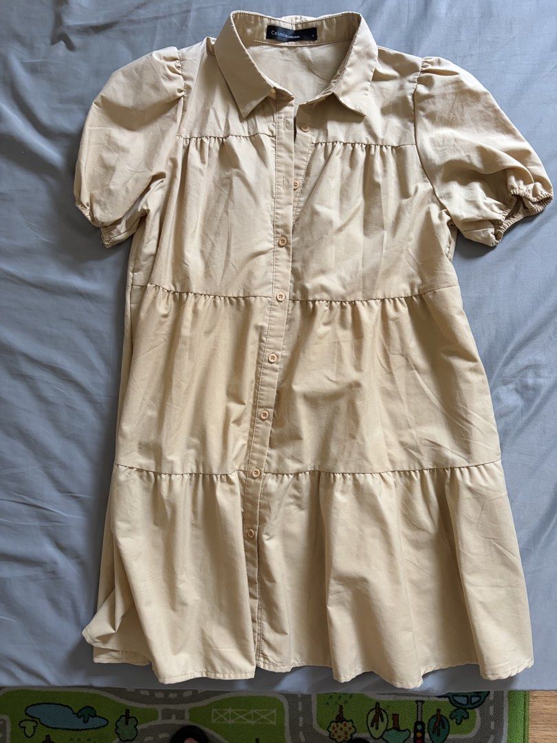 Beige Tiered Button-Up Shirt Dress (Category: Dresses) located in Manila. Submitted by anayells (Listing ID 1449010346, Image 2). Description: - Celmia Collection beige shirt dress - Tiered design with button-up front - Short puff sleeves with elastic cuffs - Collar neckline - Ideal for casual wear.