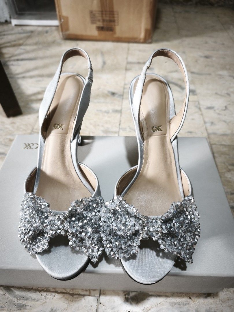 Charles & Keith Silver Slingback Heels with Bow Detail (Category: Heels) located in Manila. Submitted by icee_09 (Listing ID 1448967238, Image 1). Description: - Brand: Charles & Keith - Color: Silver - Style: Slingback heels - Features: Sparkly bow on front, clear block heel - Size: 37 - Condition: Comes with original box RFS: decluttering Shipping from Meycauayan or Makati.