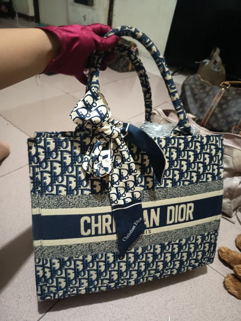 Christian Dior BOOK TOTE Large (Category: Luxury Bags & Wallets) located in San Jose del Monte. Submitted by wendylux (Listing ID 1448480733, Image 2). Description: Model Style: Dior Book Tote Pattern Motif: Blue Dior Oblique Embroidery Design Elements: Front horizontal band displaying the capitalized "CHRISTIAN DIOR" signature. Accessories: Silk scarf/twilly tied into a bow at the base of the handle. good condition.