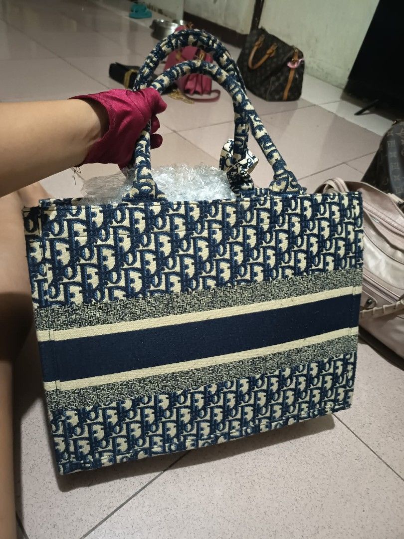 Christian Dior BOOK TOTE Large (Category: Luxury Bags & Wallets) located in San Jose del Monte. Submitted by wendylux (Listing ID 1448480733, Image 3). Description: Model Style: Dior Book Tote Pattern Motif: Blue Dior Oblique Embroidery Design Elements: Front horizontal band displaying the capitalized "CHRISTIAN DIOR" signature. Accessories: Silk scarf/twilly tied into a bow at the base of the handle. good condition.