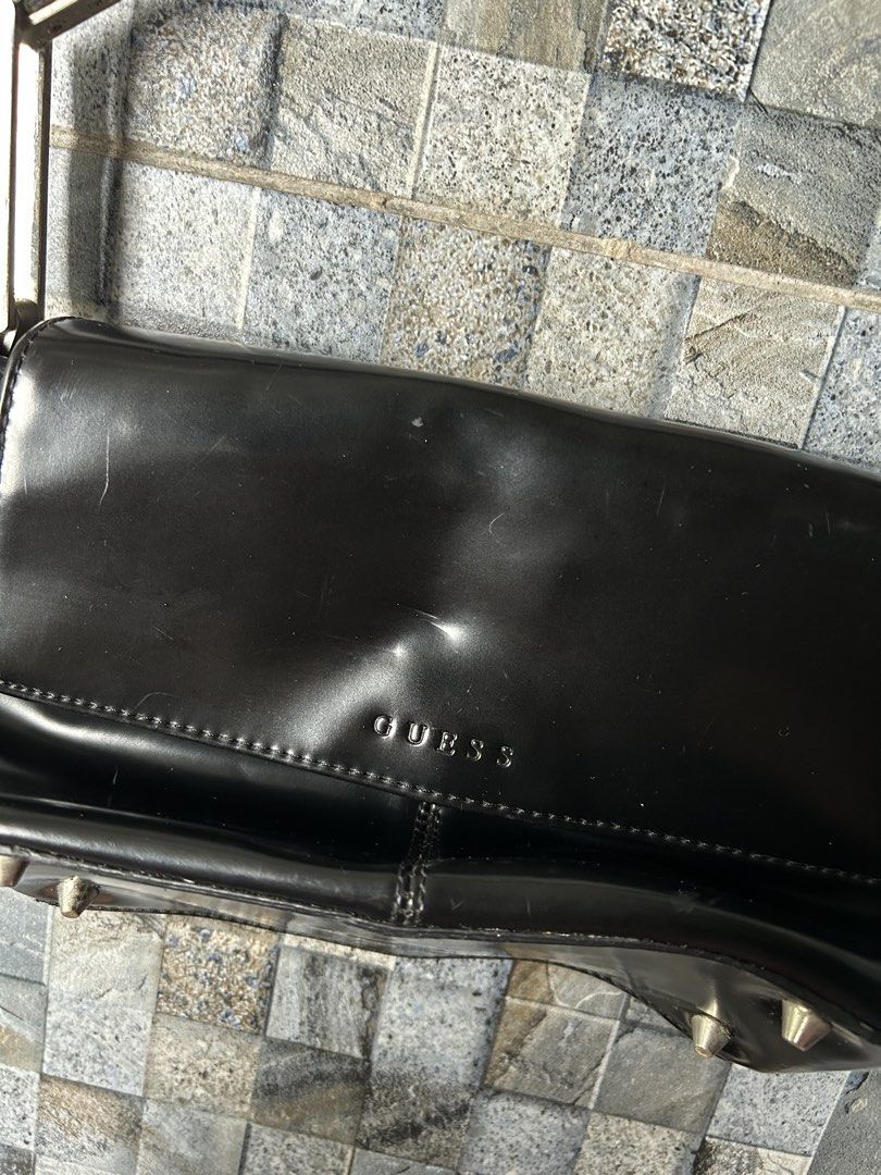 Guess Black Patent leather shoulder bag (Category: Shoulder Bags) located in Quezon City. Submitted by commonwealthpickerph (Listing ID 1448968661, Image 3). Description: Black Guess shoulder bag. - 11 width // 5.5 length - Shiny material. Has the Guess logo on the front flap. - Some small scuffs on the surface. Four metal studs on the bottom. - The strap has metal hardware with the Guess logo. A classic shoulder bag style. - Has sign of used - N