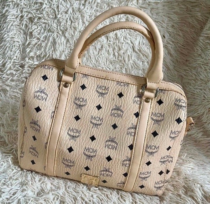 MCM Monogram Boston Bag korea (Category: Luxury Bags & Wallets) located in Caloocan City. Submitted by noy5o1a (Listing ID 1448997565, Image 1). Description: - Classic MCM monogram Boston bag - Color: Beige with navy blue MCM pattern - Material: Leather handles and trim - Interior: Zip pocket and detachable strap - Spacious design, ideal for everyday use -mcm korea.