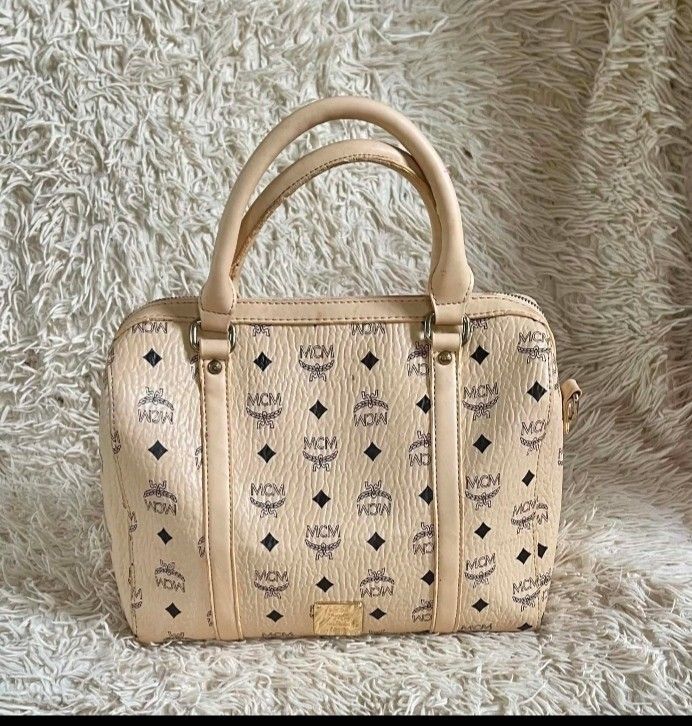 MCM Monogram Boston Bag korea (Category: Luxury Bags & Wallets) located in Caloocan City. Submitted by noy5o1a (Listing ID 1448997565, Image 2). Description: - Classic MCM monogram Boston bag - Color: Beige with navy blue MCM pattern - Material: Leather handles and trim - Interior: Zip pocket and detachable strap - Spacious design, ideal for everyday use -mcm korea.