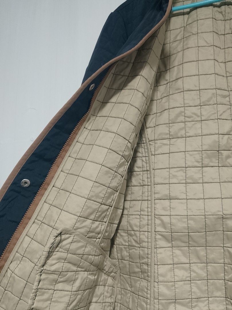 Quilted Navy Blue Jacket with Tan Trim (Category: Coats, Jackets and Outerwear) located in Baguio. Submitted by buenobueno (Listing ID 1449082054, Image 3). Description: - Navy blue quilted jacket - Tan trim on collar, pockets, and front opening - Light beige lining with a grid pattern - Two visible snap buttons for closure - Zippered side pockets - Versatile for cooler weather.