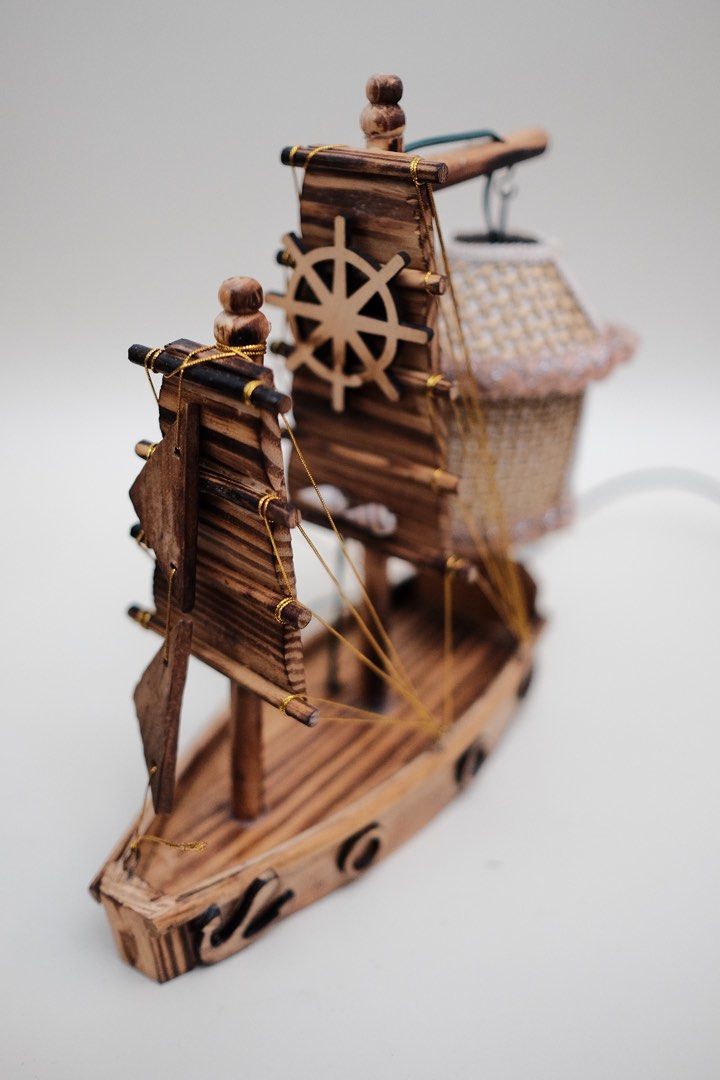 Wooden Sailboat Lamp with Lantern Shade (Category: Lighting) located in Quezon City. Submitted by fabfabuys (Listing ID 1449005641, Image 3). Description: - Unique sailboat-shaped desk lamp - Woven lantern shade for warm lighting - Crafted from wood with detailed sails and ship's wheel - Ideal for nautical-themed rooms or as a statement piece - Features an inline on/off switch on the cord.