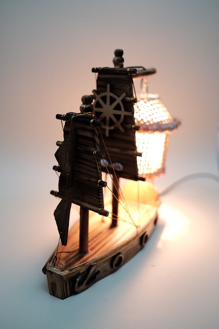 Wooden Sailboat Lamp with Lantern Shade (Category: Lighting) located in Quezon City. Submitted by fabfabuys (Listing ID 1449005641, Image 2). Description: - Unique sailboat-shaped desk lamp - Woven lantern shade for warm lighting - Crafted from wood with detailed sails and ship's wheel - Ideal for nautical-themed rooms or as a statement piece - Features an inline on/off switch on the cord.