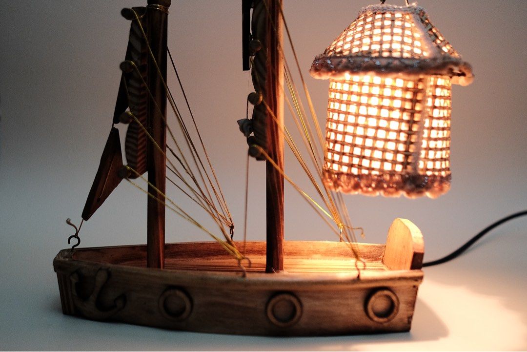 Wooden Sailboat Lamp with Lantern Shade (Category: Lighting) located in Quezon City. Submitted by fabfabuys (Listing ID 1449005641, Image 1). Description: - Unique sailboat-shaped desk lamp - Woven lantern shade for warm lighting - Crafted from wood with detailed sails and ship's wheel - Ideal for nautical-themed rooms or as a statement piece - Features an inline on/off switch on the cord.