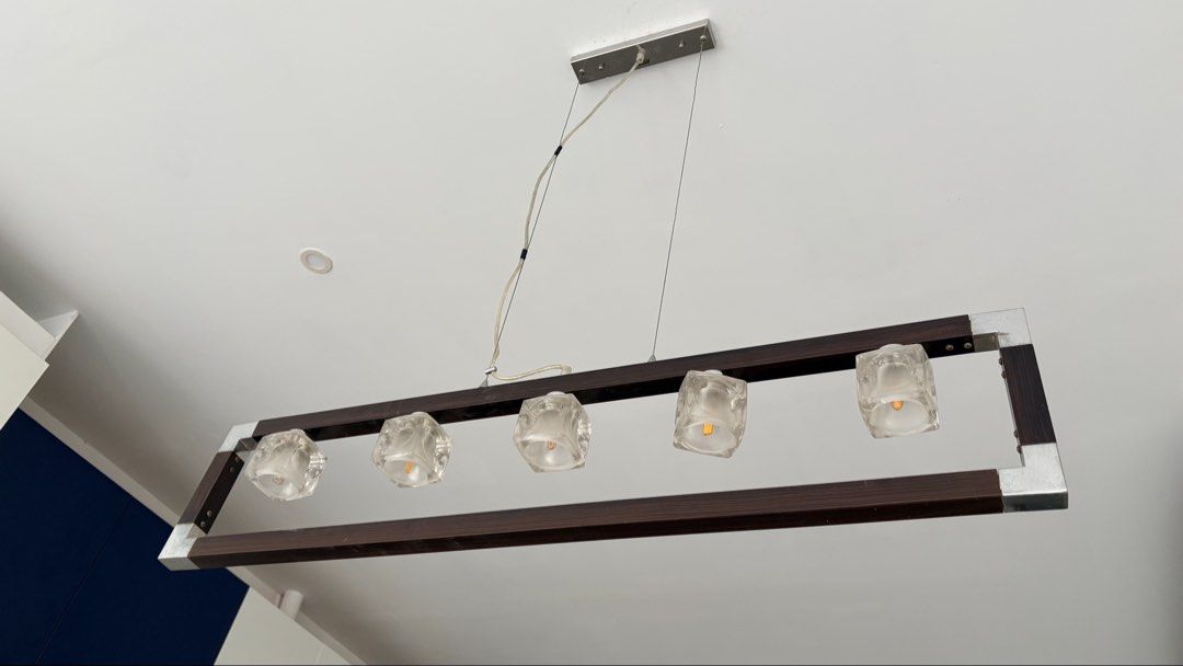 5-Light Rectangular Pendant Chandelier Wood and Metal Frame (Category: Lighting) located in Paranaque City. Submitted by allymadamba (Listing ID 1449157769, Image 2). Description: - Elegant rectangular pendant light - Combines wood and metal frame for a modern look - Features 5 clear glass shades - Ideal for illuminating dining tables or kitchen islands - Provides warm, inviting illumination - Dimensions: 90 cm (Length) x 20 cm (Height), Total dr