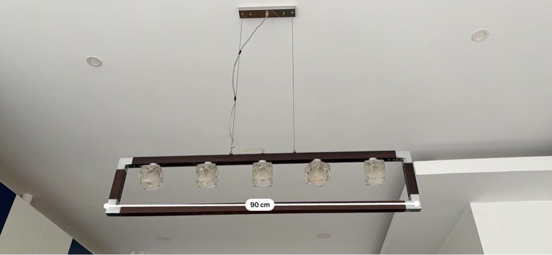5-Light Rectangular Pendant Chandelier Wood and Metal Frame (Category: Lighting) located in Paranaque City. Submitted by allymadamba (Listing ID 1449157769, Image 3). Description: - Elegant rectangular pendant light - Combines wood and metal frame for a modern look - Features 5 clear glass shades - Ideal for illuminating dining tables or kitchen islands - Provides warm, inviting illumination - Dimensions: 90 cm (Length) x 20 cm (Height), Total dr
