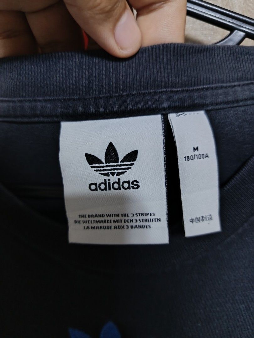 Adidas T-Shirt Size M (Category: Tshirts & Polo Shirts ) located in Jasaan. Submitted by eliwhomp (Listing ID 1449278861, Image 3). Description: - Navy blue Adidas t-shirt - Size: Medium (M) - Front: Stacked Adidas logo in various colors - Back: Repeating Adidas logo pattern - Material: 100% Cotton - 21 × 29.