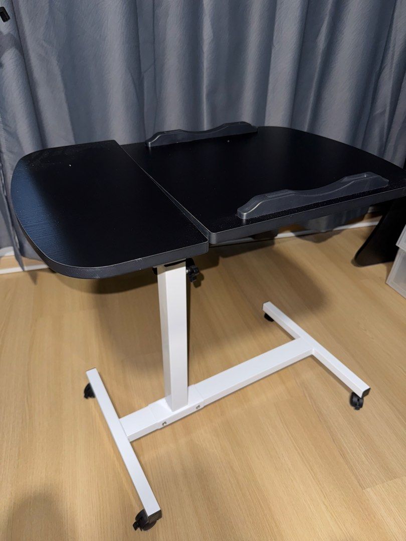 adjustable table (Category: Tables & Sets) located in Singapore. Submitted by yitiao (Listing ID 1449110122, Image 1). Description: - Black adjustable laptop table - White metal base with wheels for easy mobility - Adjustable height via side knobs - Tilting tabletop - Ideal for working in bed or on the sofa - Compact and functional design.