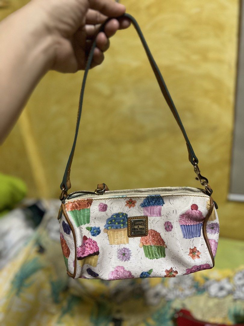 Dooney & Bourke Cupcake Print Small Shoulder Bag (Category: Luxury Bags & Wallets) located in Quezon City. Submitted by cprmob (Listing ID 1449109192, Image 1). Description: - Cute Dooney & Bourke shoulder bag - Fun all-over cupcake print on a white background - Colorful cupcake design - Genuine leather trim and strap - Secure zipper closure - Interior lined in blue - Perfect for adding a playful touch to your outfit.