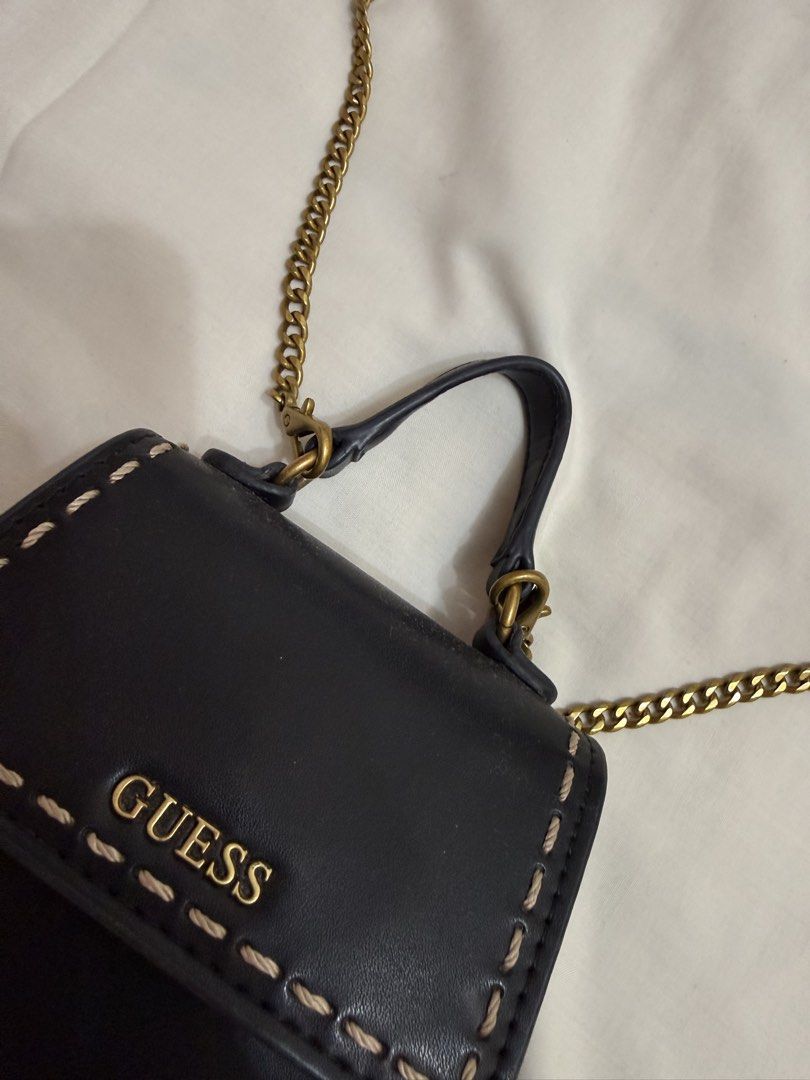 Guess Black Mini Bag with Gold Chain (Category: Luxury Bags & Wallets) located in Makati City. Submitted by haggleandshop (Listing ID 1449255936, Image 2). Description: - Cute black mini bag from Guess - Gold chain strap and top handle - Stitching detail on the front flap - Small size, ideal for essentials - Interior features Guess logo - Gold hardware - Versatile for night outs or casual wear.