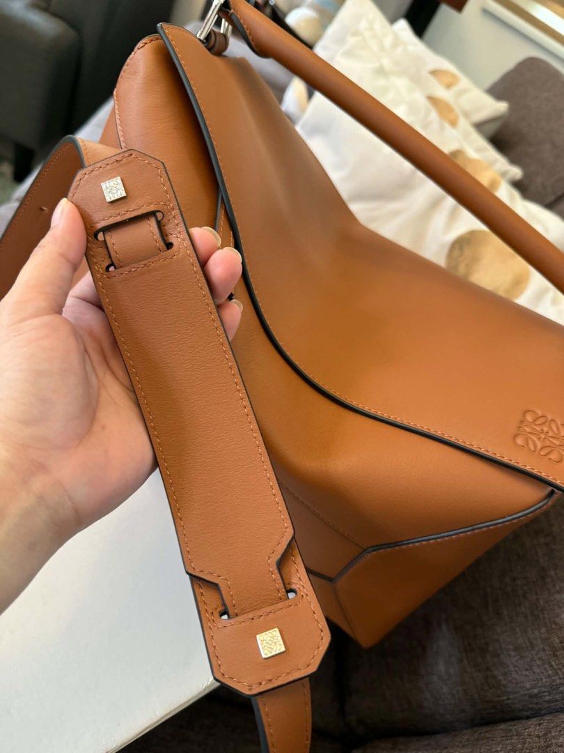 Loewe Puzzle Hobo Bag Tan Leather (Medium Size) (Category: Luxury Bags & Wallets) located in Hermosa. Submitted by bookwormhermosa (Listing ID 1449121408, Image 3). Description: - Loewe Puzzle - Color: Tan leather - Includes original box and dust bag - Detachable shoulder strap included - Features the iconic Loewe Anagram logo - Ideal for everyday use - Spacious interior.