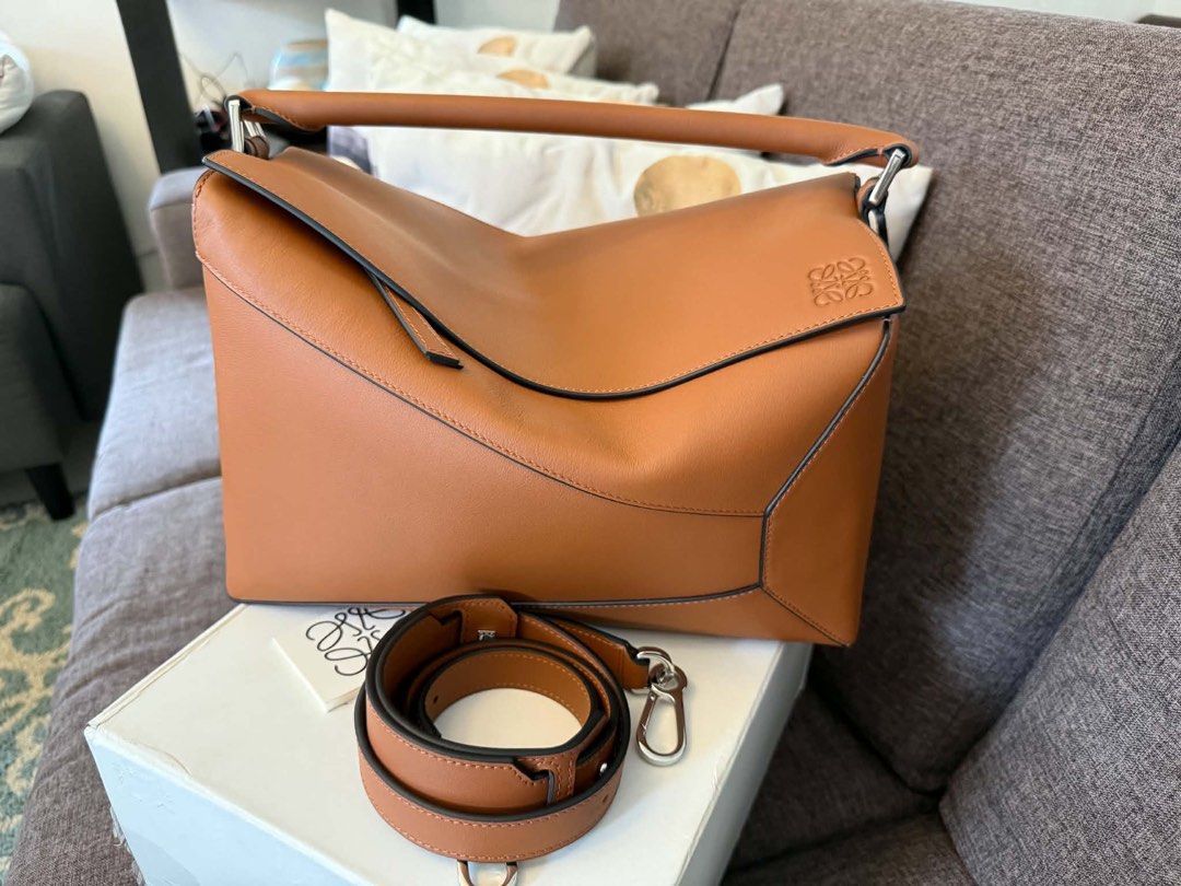 Loewe Puzzle Hobo Bag Tan Leather (Medium Size) (Category: Luxury Bags & Wallets) located in Hermosa. Submitted by bookwormhermosa (Listing ID 1449121408, Image 1). Description: - Loewe Puzzle - Color: Tan leather - Includes original box and dust bag - Detachable shoulder strap included - Features the iconic Loewe Anagram logo - Ideal for everyday use - Spacious interior.